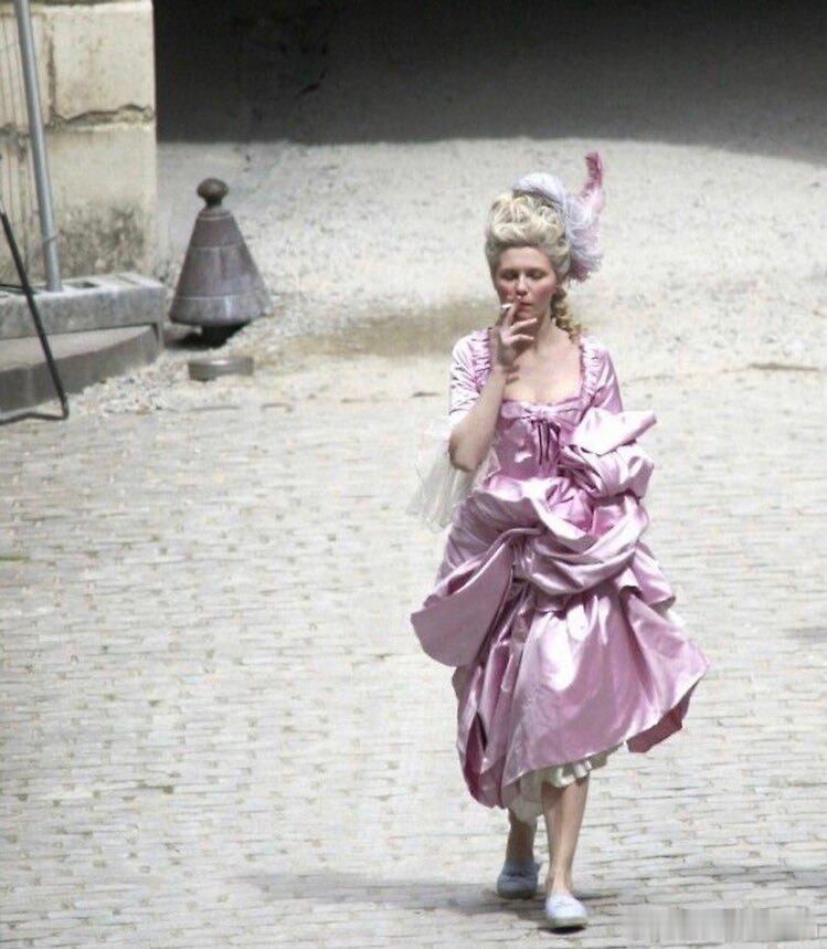 克里斯滕·邓斯特在《绝代艳后》的一张片场照，穿着洛可可风格的戏服在片场抽烟 