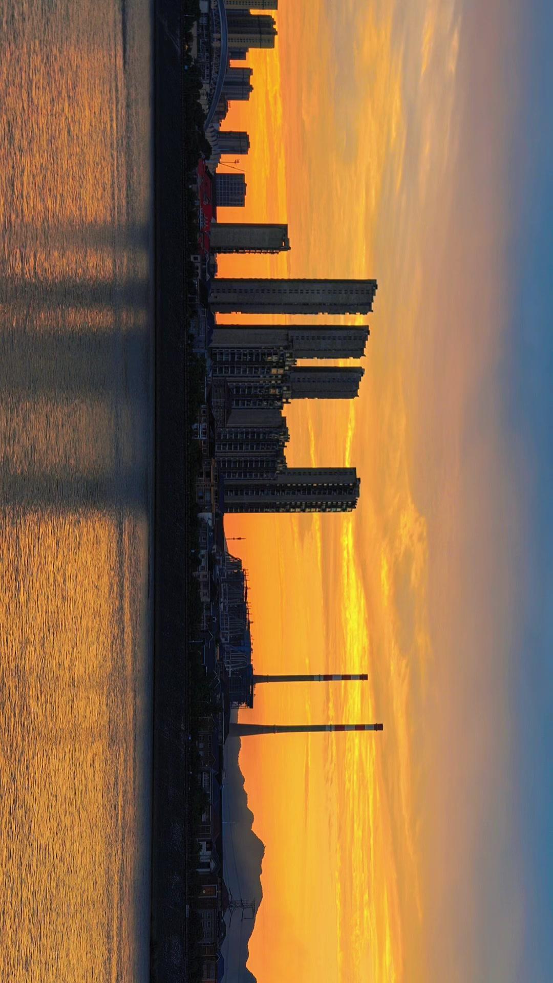 🌇橘色晚霞漫过远山，江面便铺满了落日碎金。新旧楼宇并肩伫立，连老旧烟囱都仿佛成