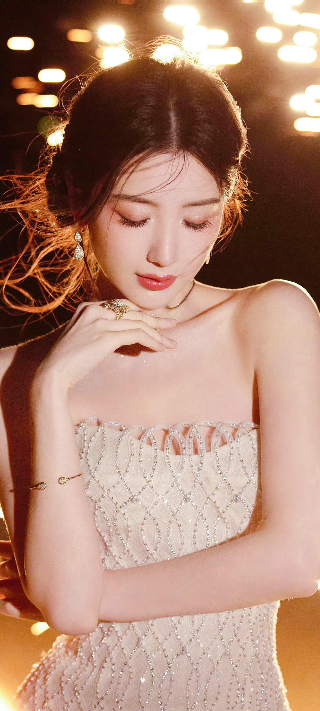 《晶裙凝光》
晶钻裁裙缀素纱，流光曳影映霞华。
青丝漫卷风前雪，朱唇轻点镜中花。