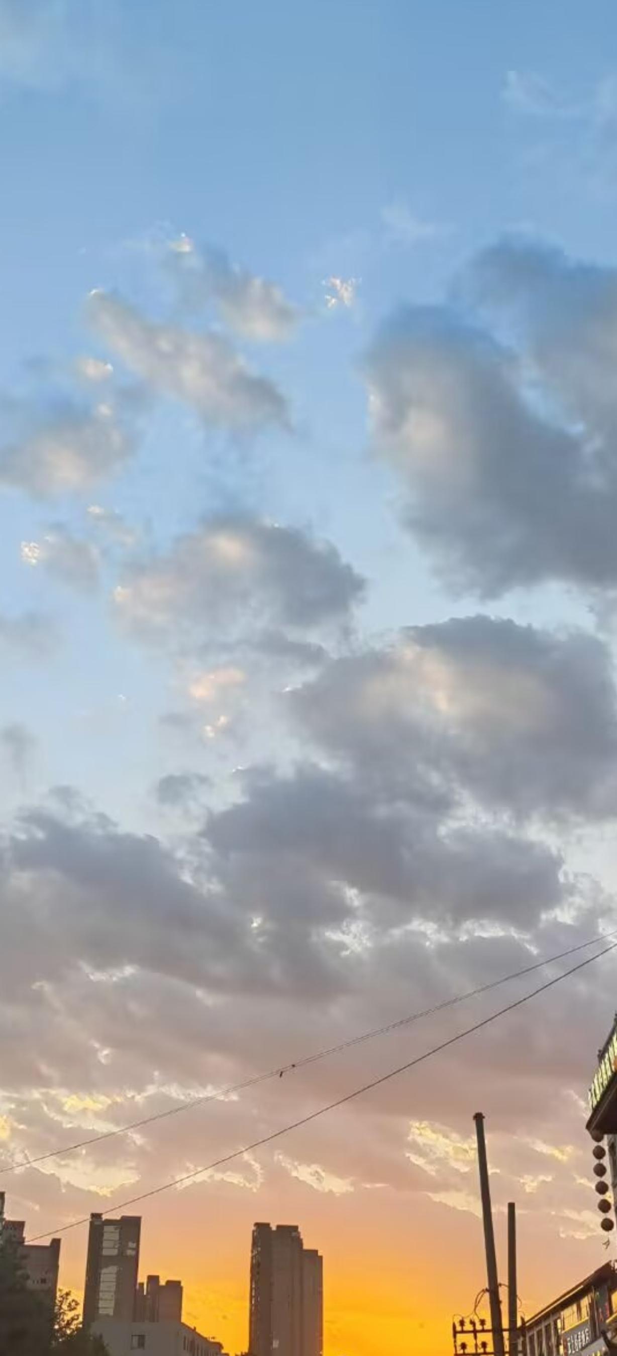 昨日下午接送孙子放学，回到小区时恰逢夕阳西下。随手定格下天边绚烂的落日美景，暖融