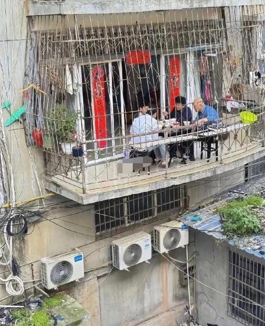 对面阳台这一幕看得心惊！老式居民楼悬空阳台，几个人围坐吃饭，仅仅一层铁网隔着高空