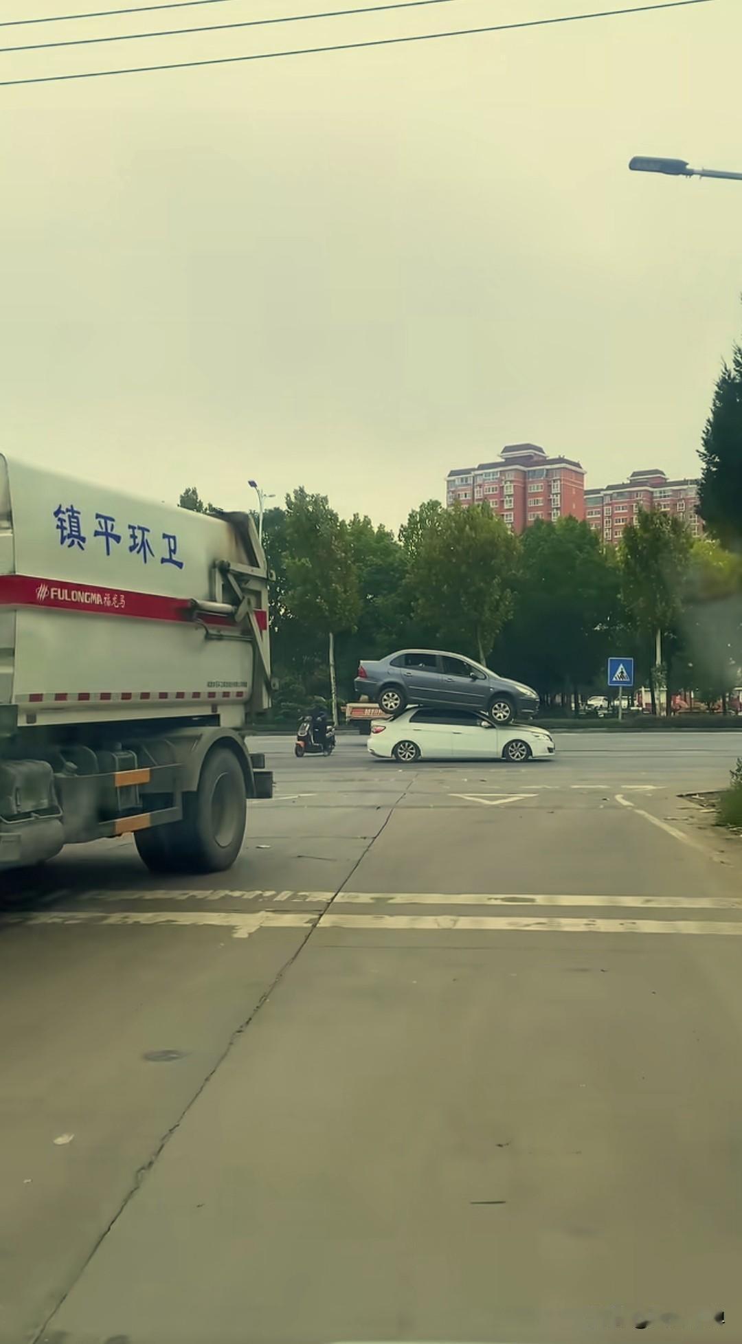 这车是怎么上去的啊？近日有网友在街头拍到一辆黑色标志和一辆白色风神竟然摞到了一起