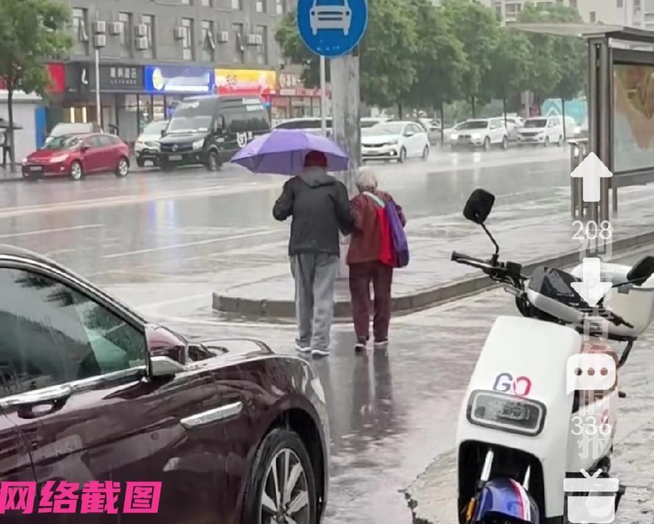 某地天空下雨，看有一对老夫妻从不远处，一起匆忙朝公交站台走去。

只是现场看大爷