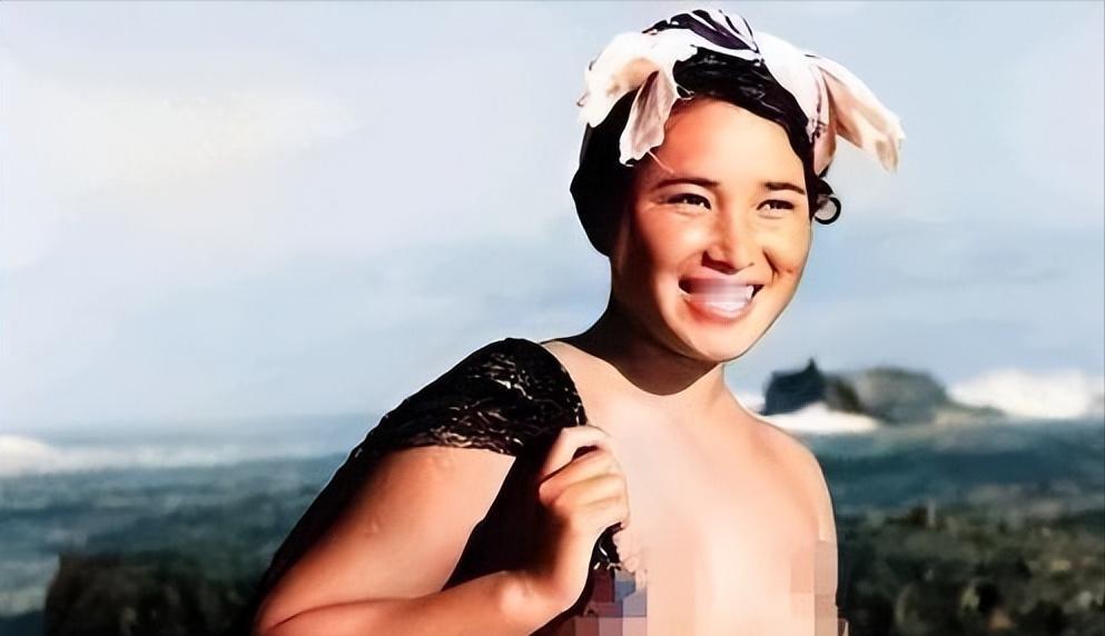 1955年，一名身体强壮的日本女人赤裸上半身，背着一个黑色的编织袋站在海边。这个