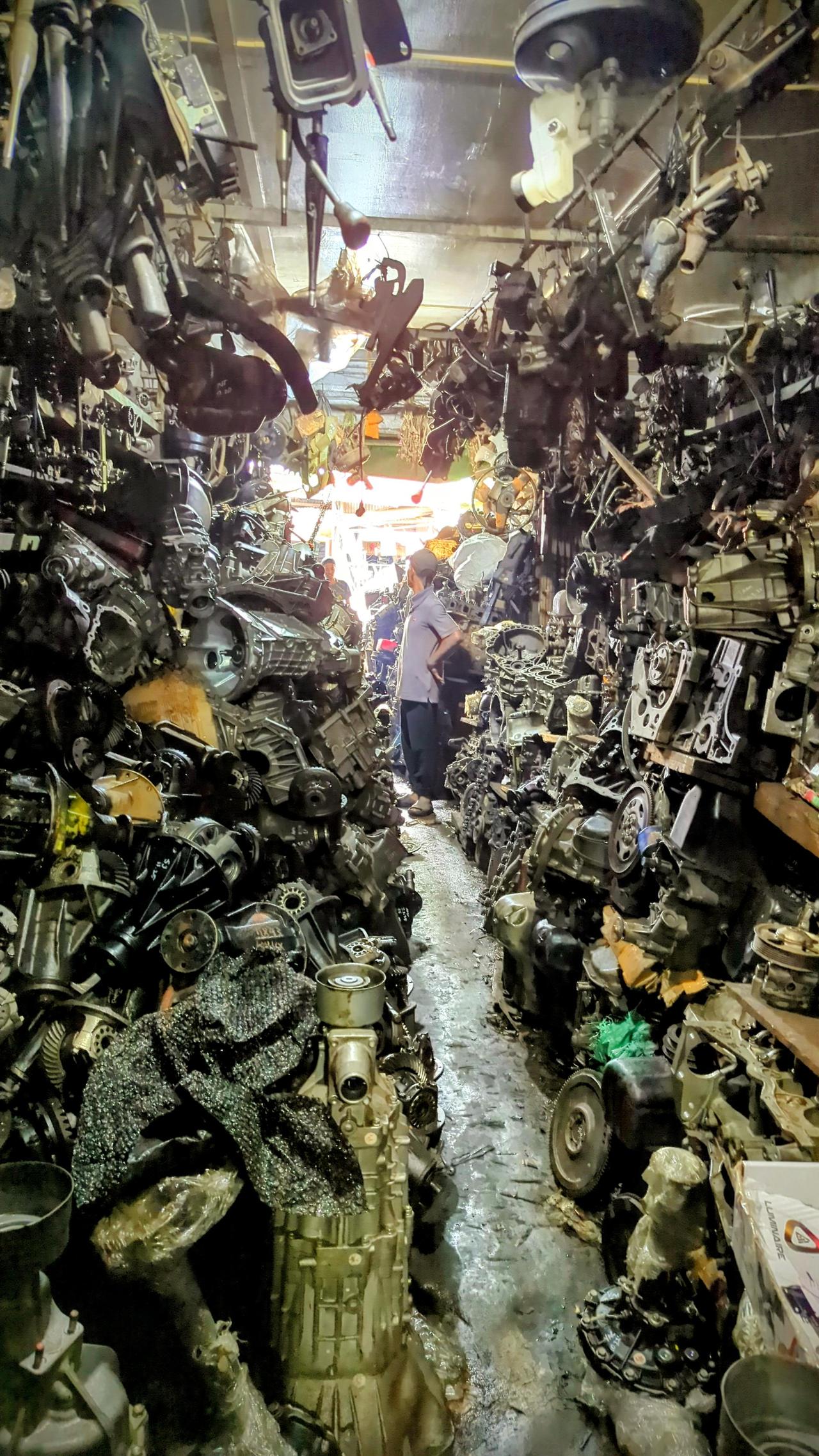 乍看是个堆满零件的杂乱店铺，但那双在发动机零件积木塔里穿的凉鞋，才真让人多看两眼