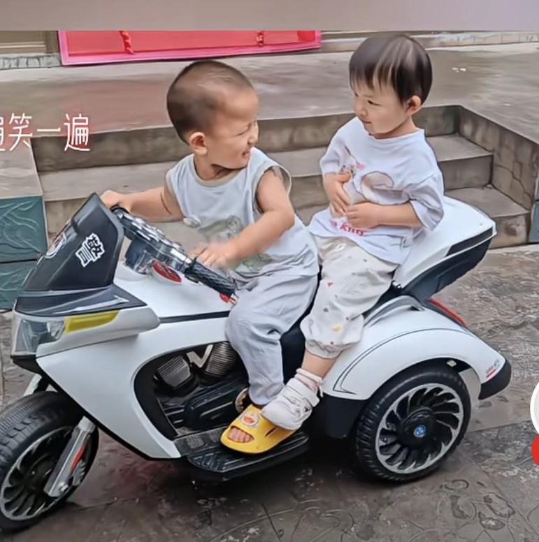 男孩骑着玩具摩托车，带着女孩玩，扭头对视，两人还拥抱，结果翻车。
网友说，说多少