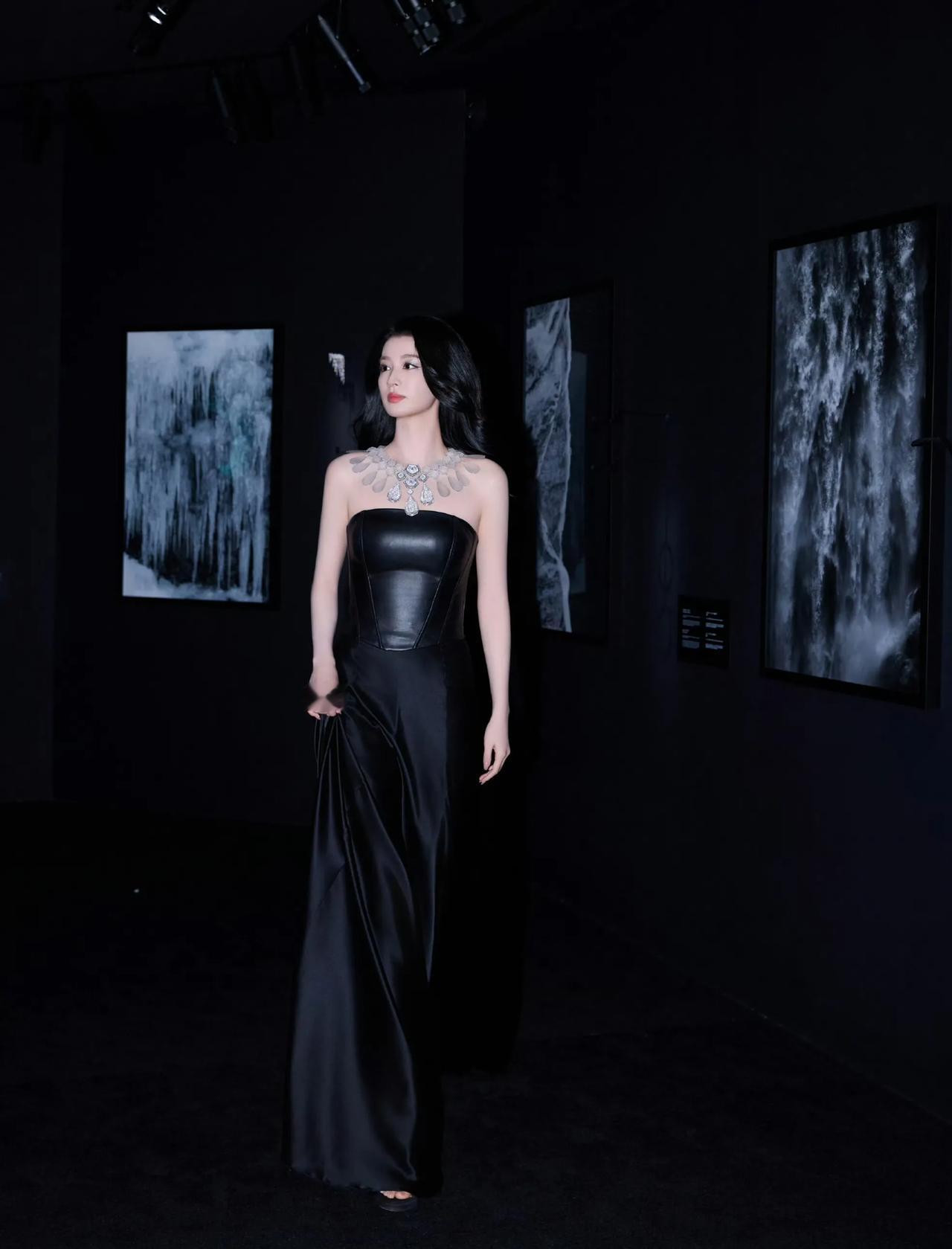 都说黑色是最神秘也是最时尚的颜色。照片中的她站在黑色的背景下，穿着一身全黑的长裙
