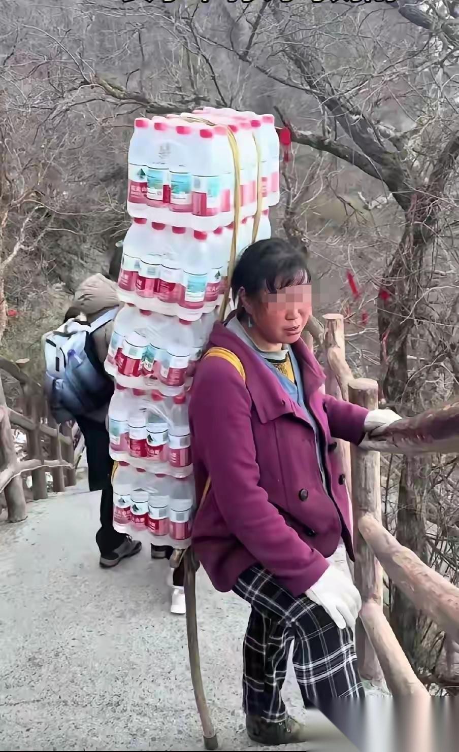 一女子背上背了120瓶500毫升的矿泉水，艰难地往山上走，看似一脸的沧桑和憔悴。