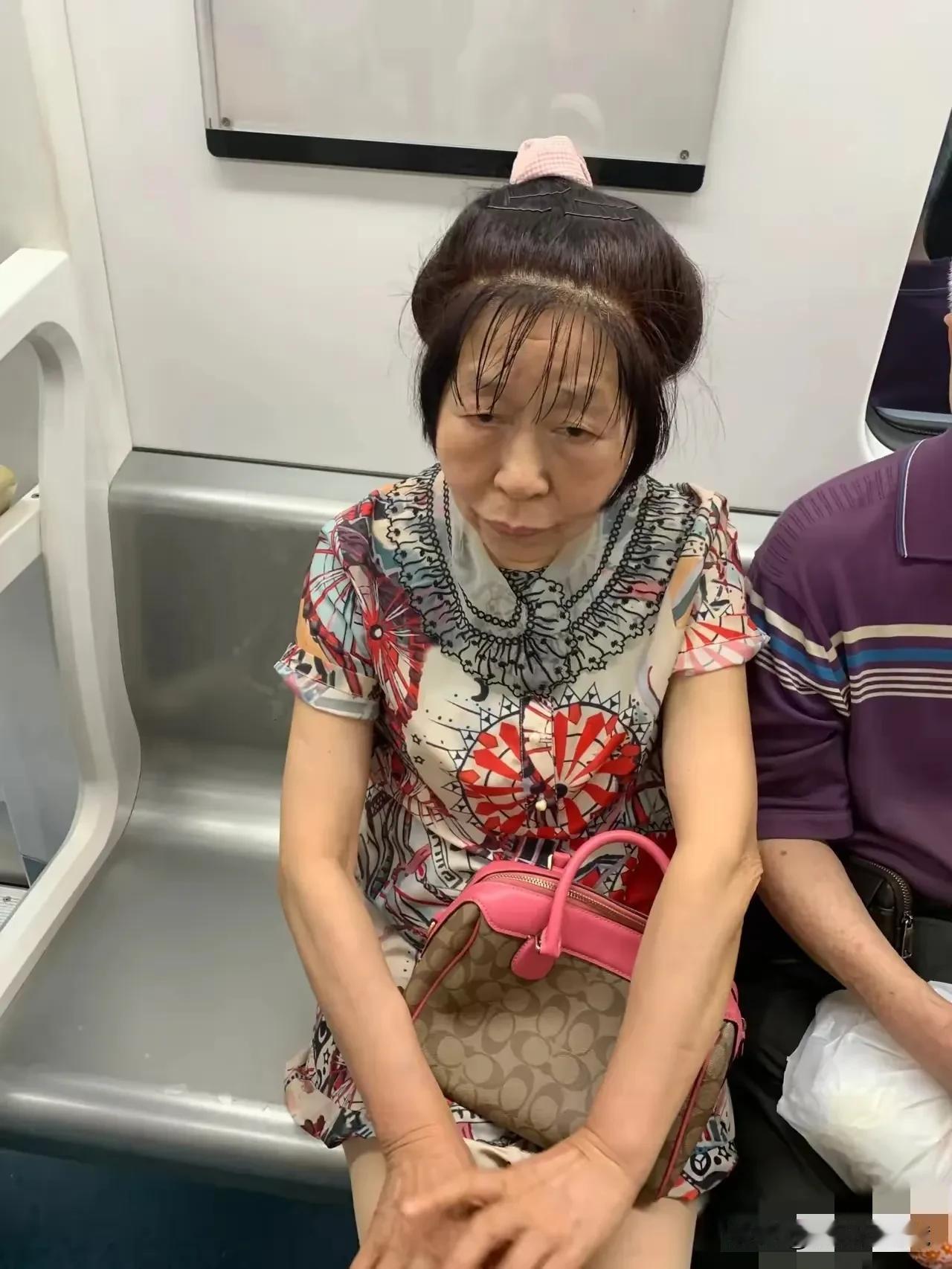 考考你的眼力，照片中这个中年妇女静静的坐在地铁车厢里，她的穿着打扮非常的特别，无
