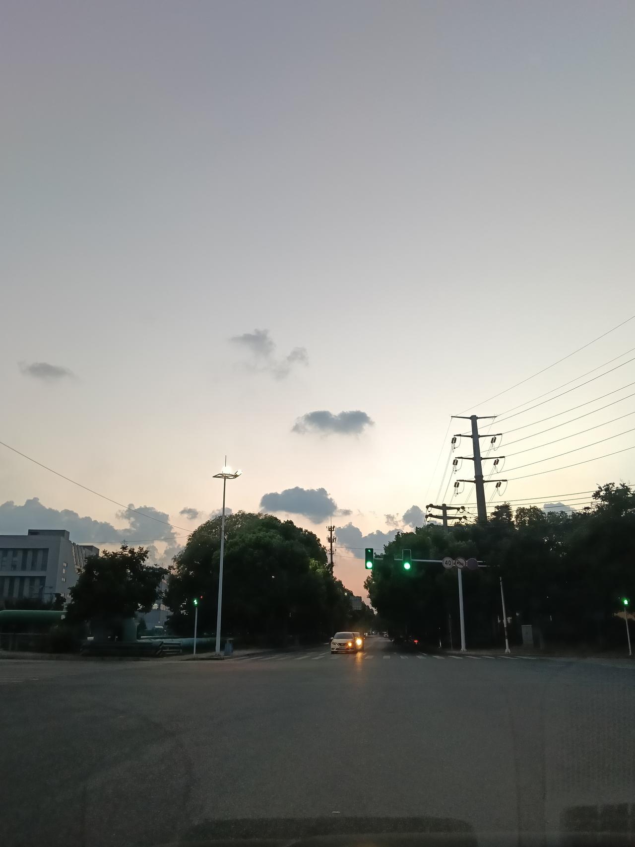 傍晚走在小城街头，晚霞漫过天际，云朵被落日染上温柔的暖橙色。街道上车流缓缓，绿树