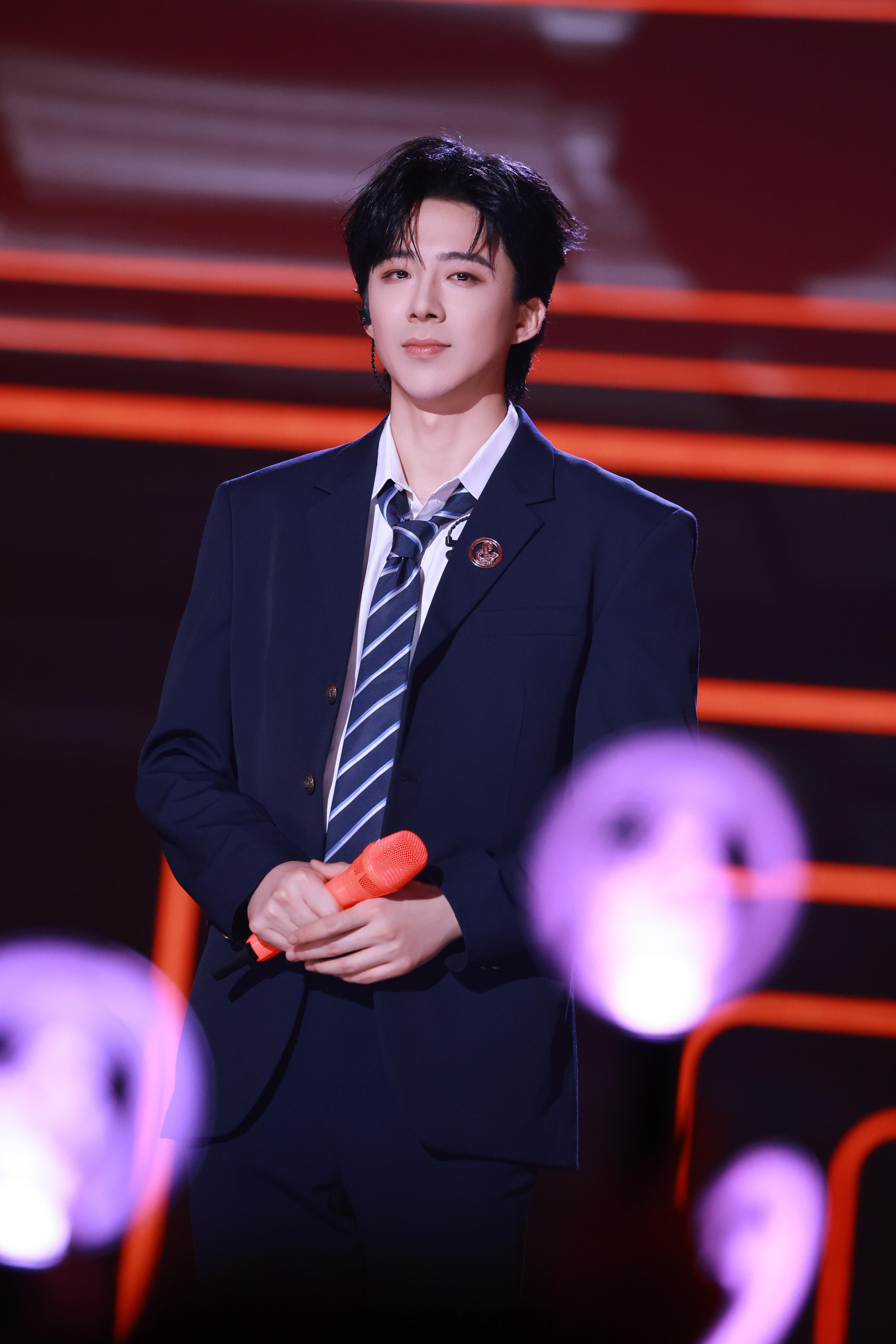 摩登兄弟[超话] 深蓝色西装搭配条纹领带，校徽点缀细节，刘宇宁手持橙色麦克风，在