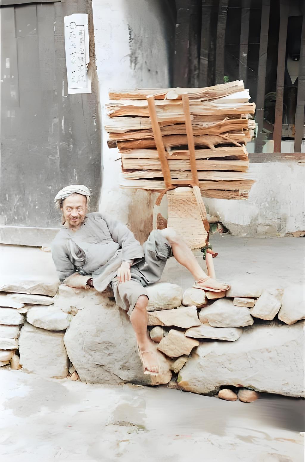 这张1944 年拍摄于山西的老照片，画面中，男子裹着头巾，靠在石块垒的矮墙上，脚