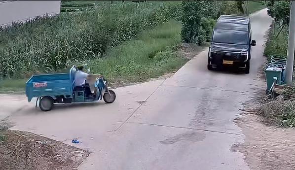 一条乡村小道的十字路口，一辆三轮车高速上主路。恰好前方来车，三轮车听到鸣笛声。猛