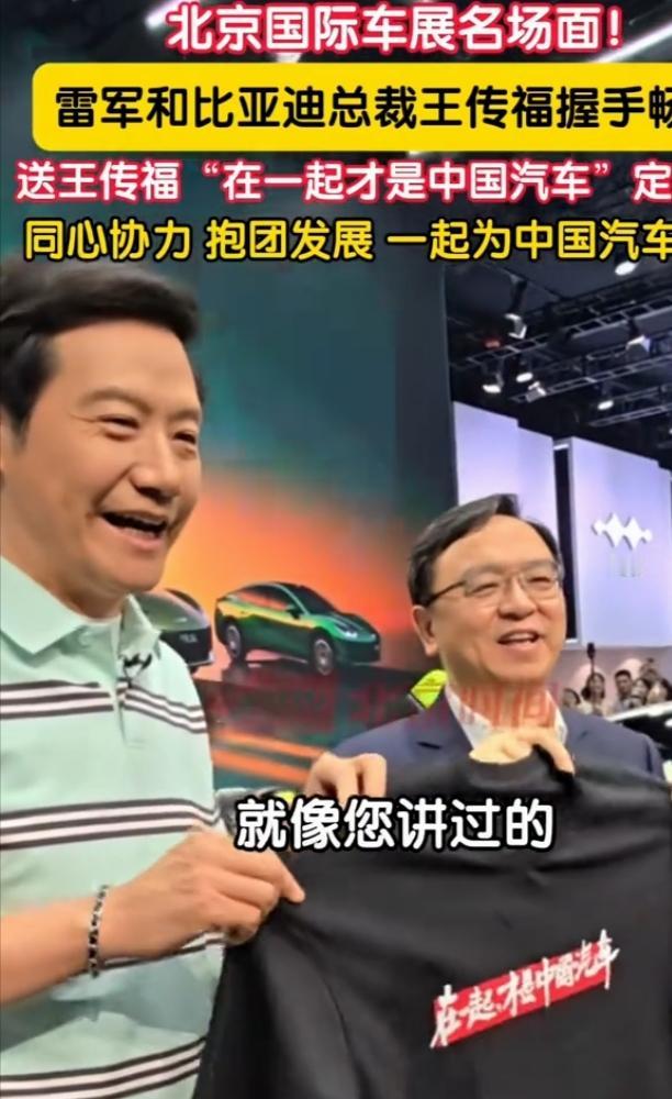 北京车展现场上演超有爱一幕，雷军逛到比亚迪展台，当场给王传福送上一件定制T恤，上