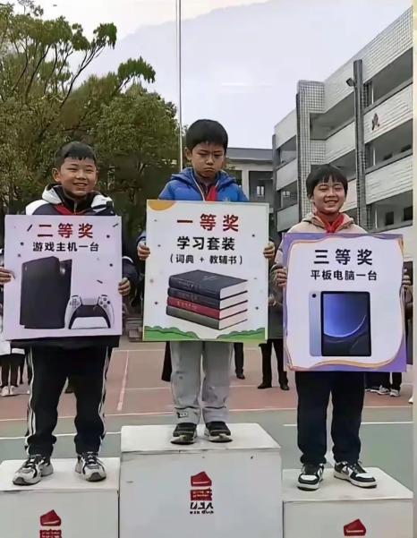 颁奖台的格局直接颠覆认知，一等奖是厚重的学习教辅套装，二等奖游戏主机，三等奖平板