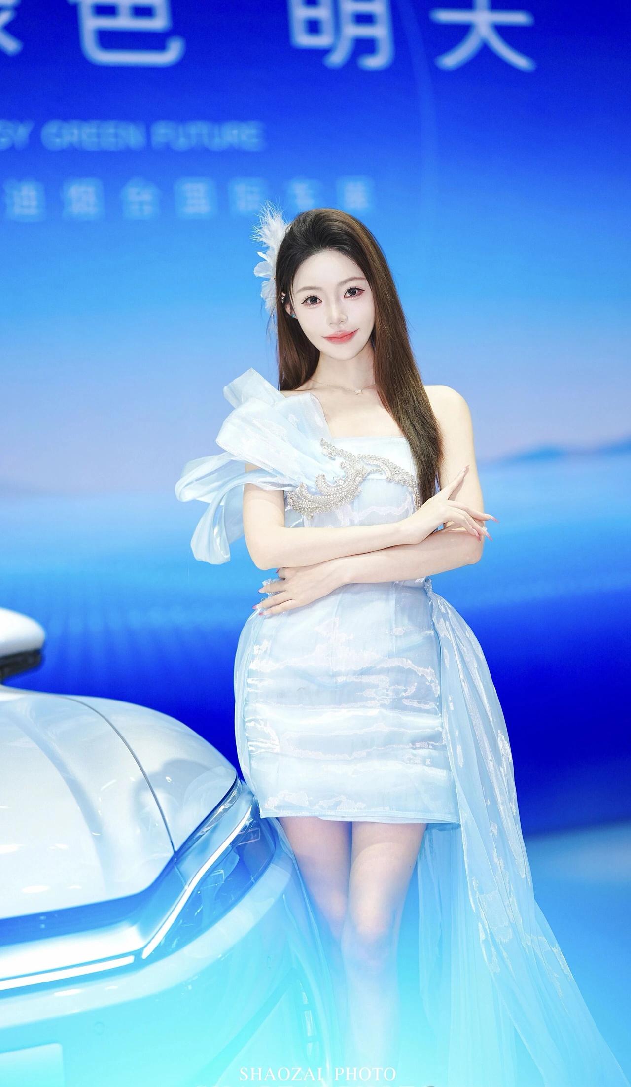 裙装是单肩设计，一侧大荷叶纱袖轻盈蓬松，胸口缀有精致水钻装饰，短款裙身搭配飘逸拖