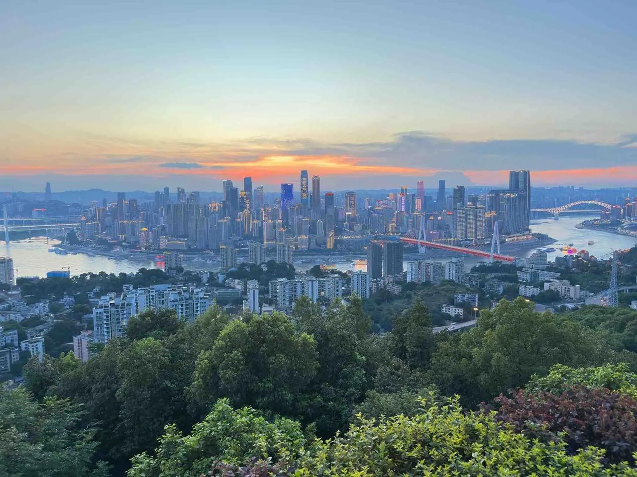 盛夏的清晨，南山俯瞰整座重庆。
日出把天际晕染成橘色，两江缓缓流淌，城市还未完全