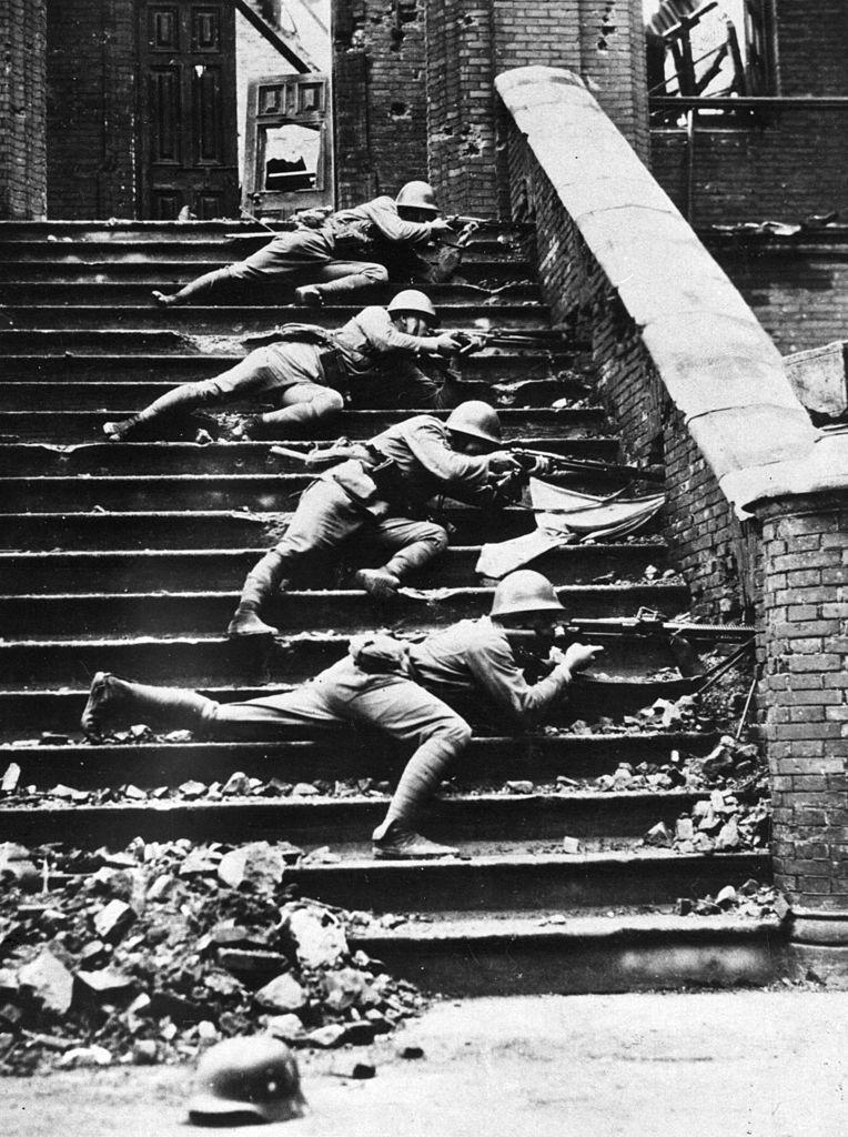 1937年10月，上海闸北，日军步兵透过砖墙的孔洞向中方阵地开火。