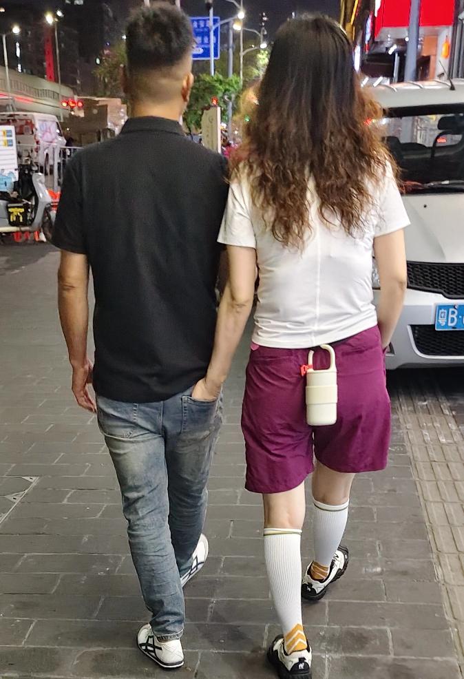 照片上的这对男女穿着普通，但发型时尚，其步子稳健而有节奏。
    长发女士显得