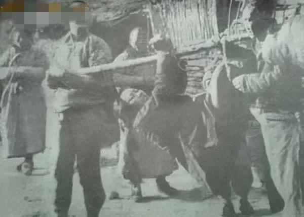 晚清时期，一名即将被“浸猪笼”的妇女，照片中的她四肢被捆在一起，众人用一根木棒抬