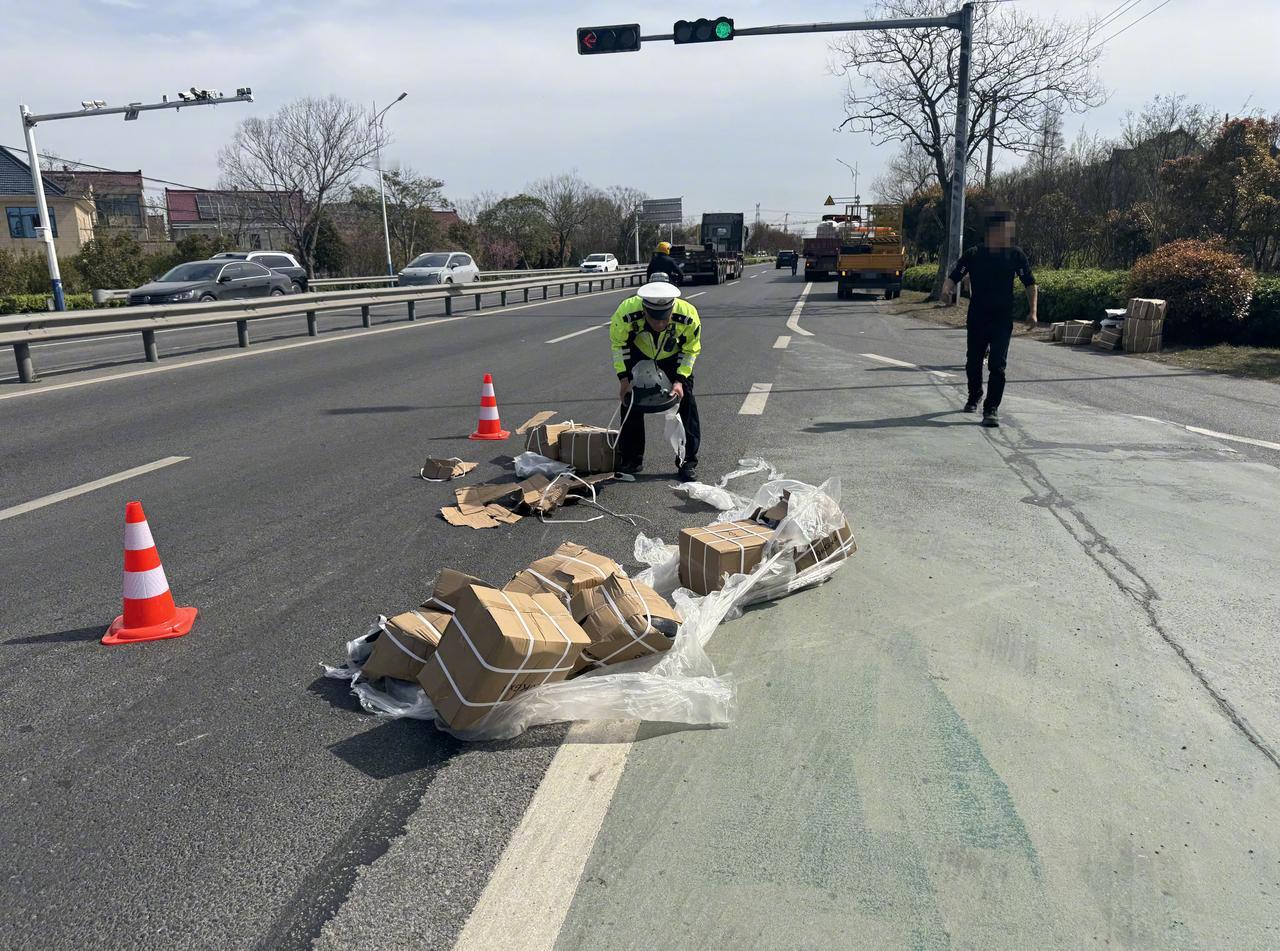 【货车货物洒落路面 交警快速处置消隐患】近日，如皋市吴窑镇一路口，一辆货车因急转