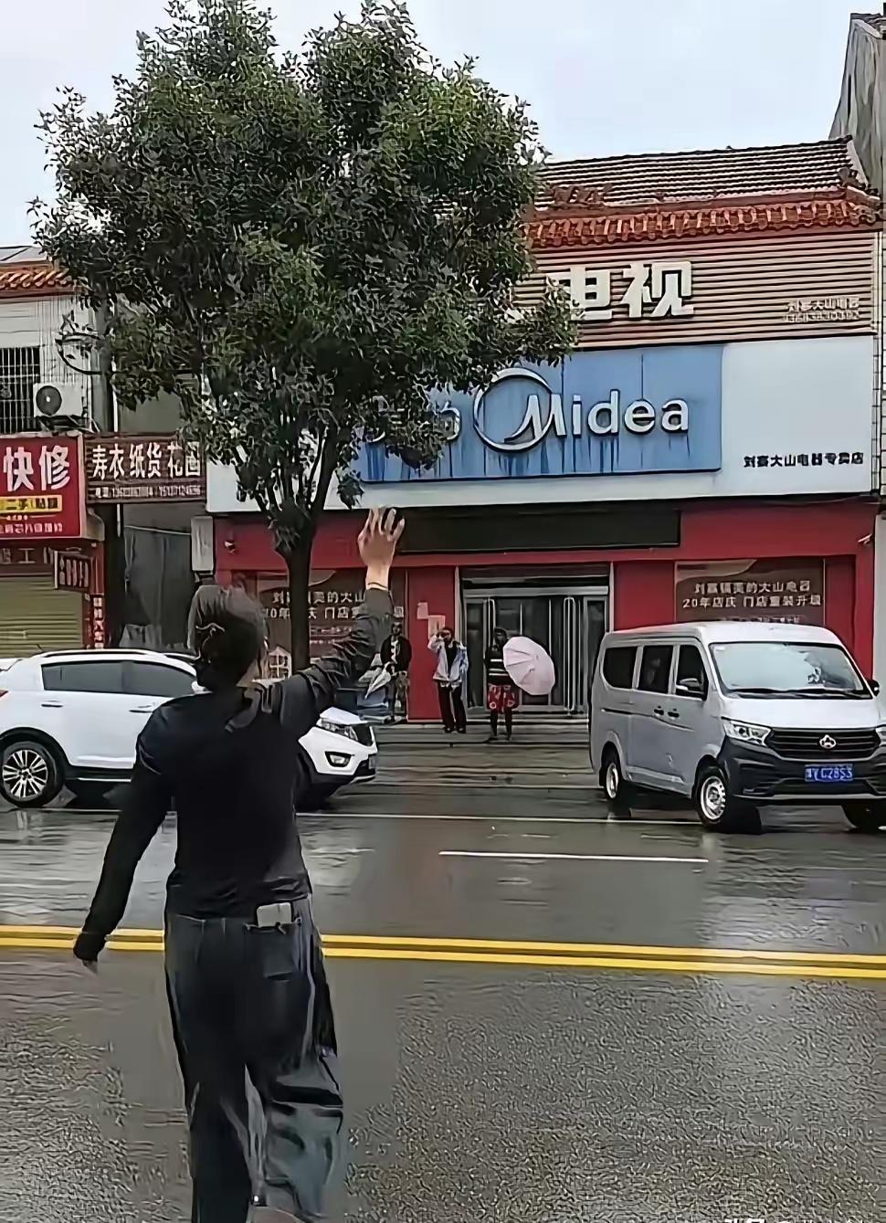 河南街头突然下起大雨，四名外国人匆忙跑到屋檐下躲雨，马路对面两名姑娘看见之后，黑