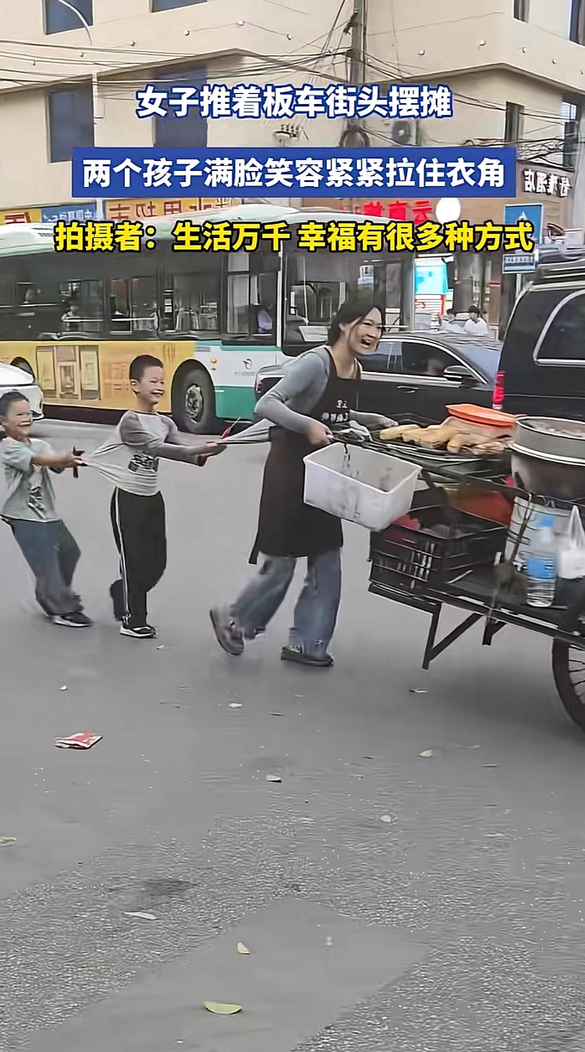 刷到那个女子拖大板车摆地摊的视频，瞬间就被戳中了。
两个小儿子一左一右拽着她的衣