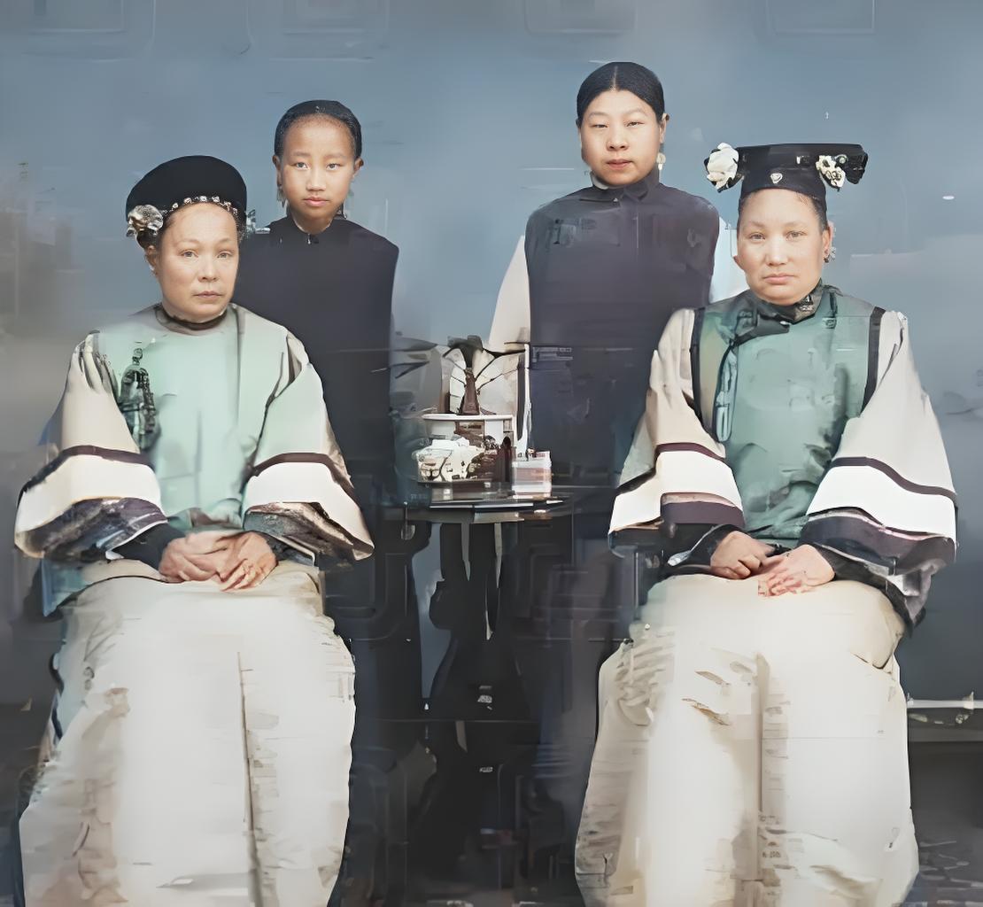 这张晚清老照片呈现了一个典型的旗人家庭场景。画面中两位端坐的女性身着精致旗装，头