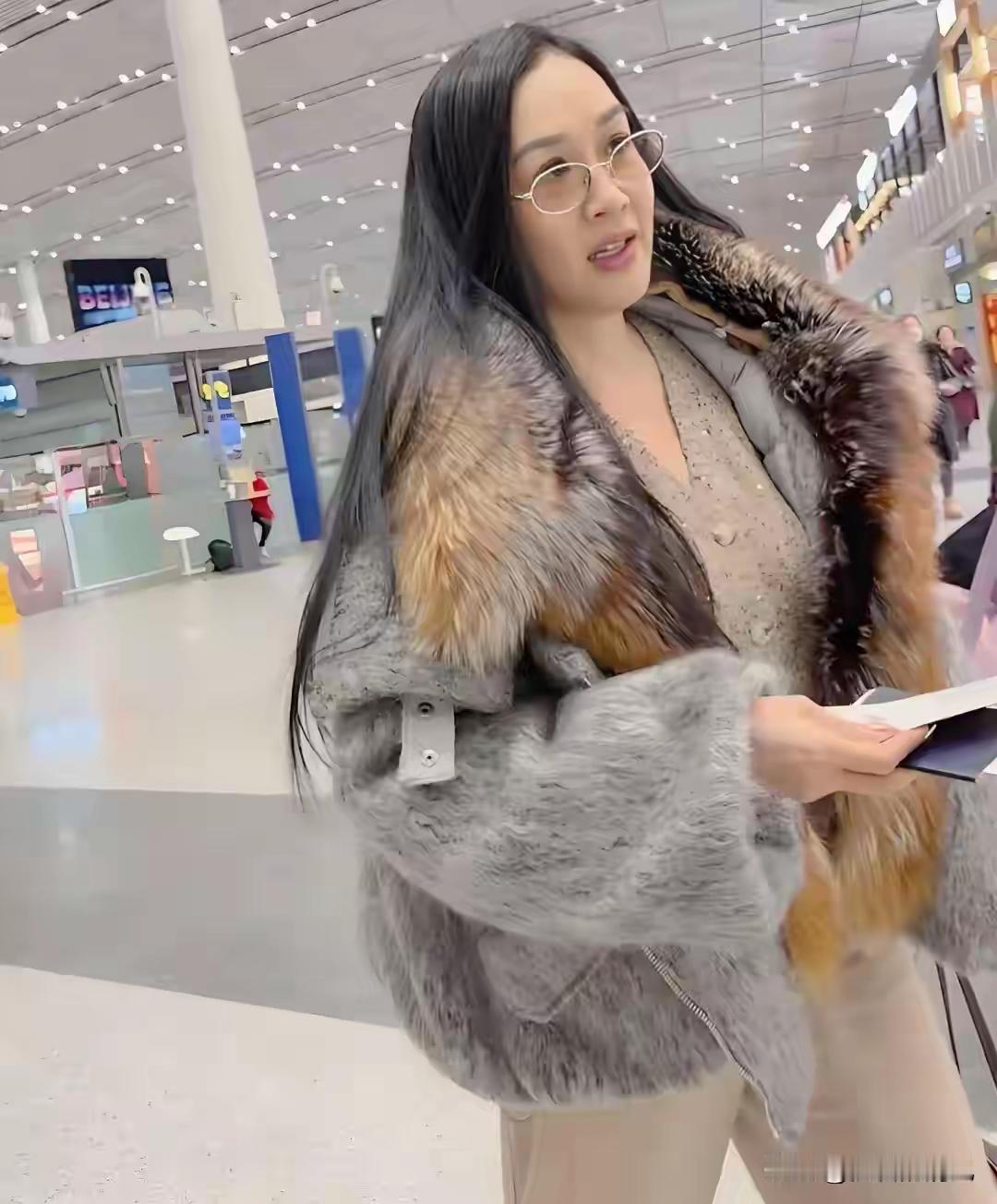 55岁的钟丽缇机场穿棕色长毛大衣，直接把话题度拉满。那大衣毛量大、颜色厚重，她一