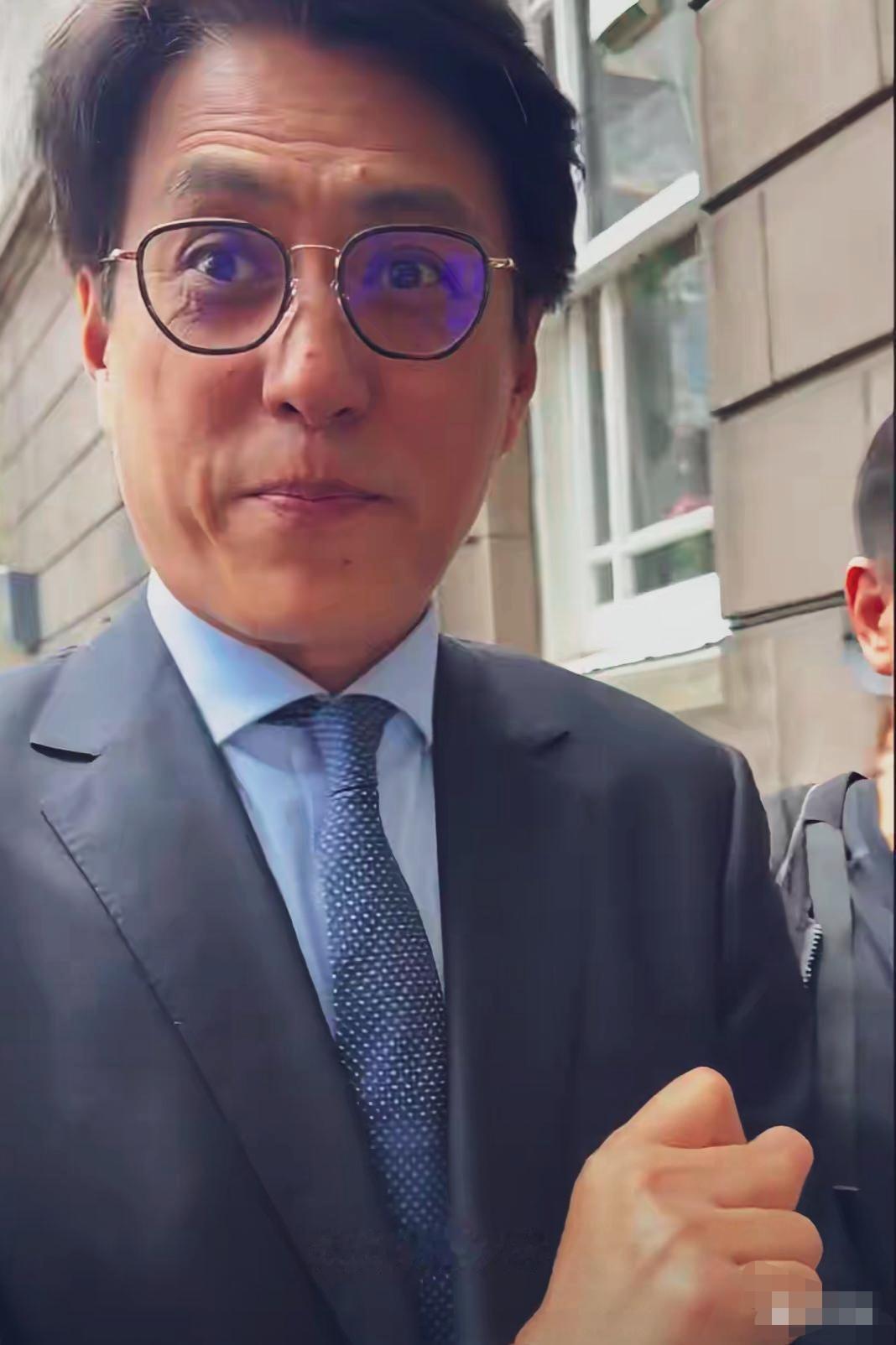 英国街头网友抓拍。
靳东面对镜头，双眼睁大，嘴角抿起，神情温和。脸上皱纹明显，男