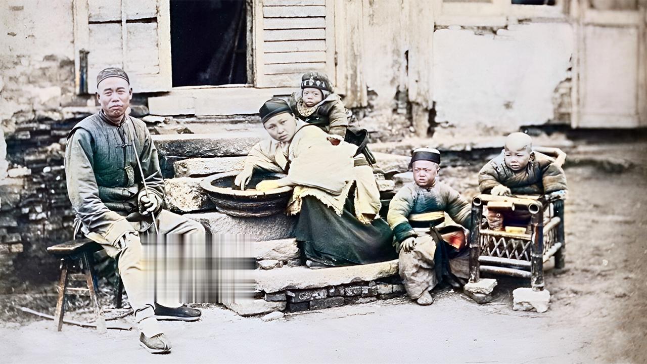 这是晚清时期，一个温饱之家，一家五口人在门口留下的一张照片。

这个男人坐在凳子