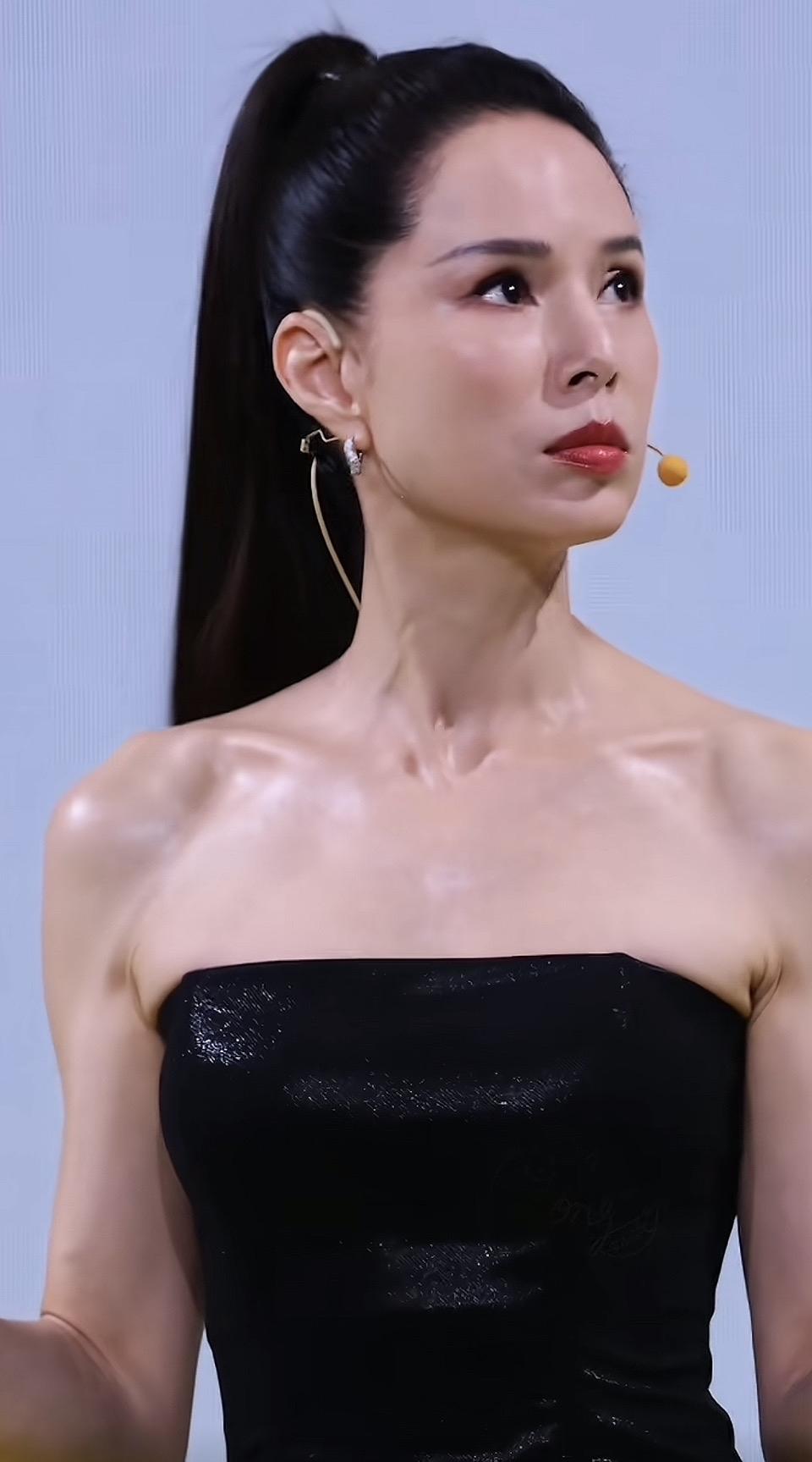 这位女士穿着黑色礼服，耳朵上戴着耳环。