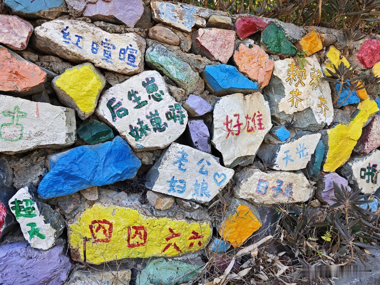 在黄花湾的一处停车场附近，有这么一条写满了客家方言的围墙，在每一块石板上面，艺术