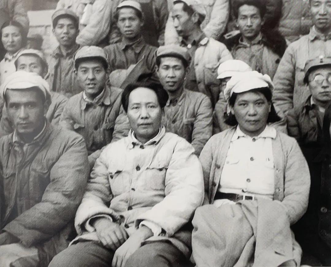 1942 年延安杨家岭，毛主席坐在人群中，身上是一件洗得发白、带着针脚的厚棉衣，