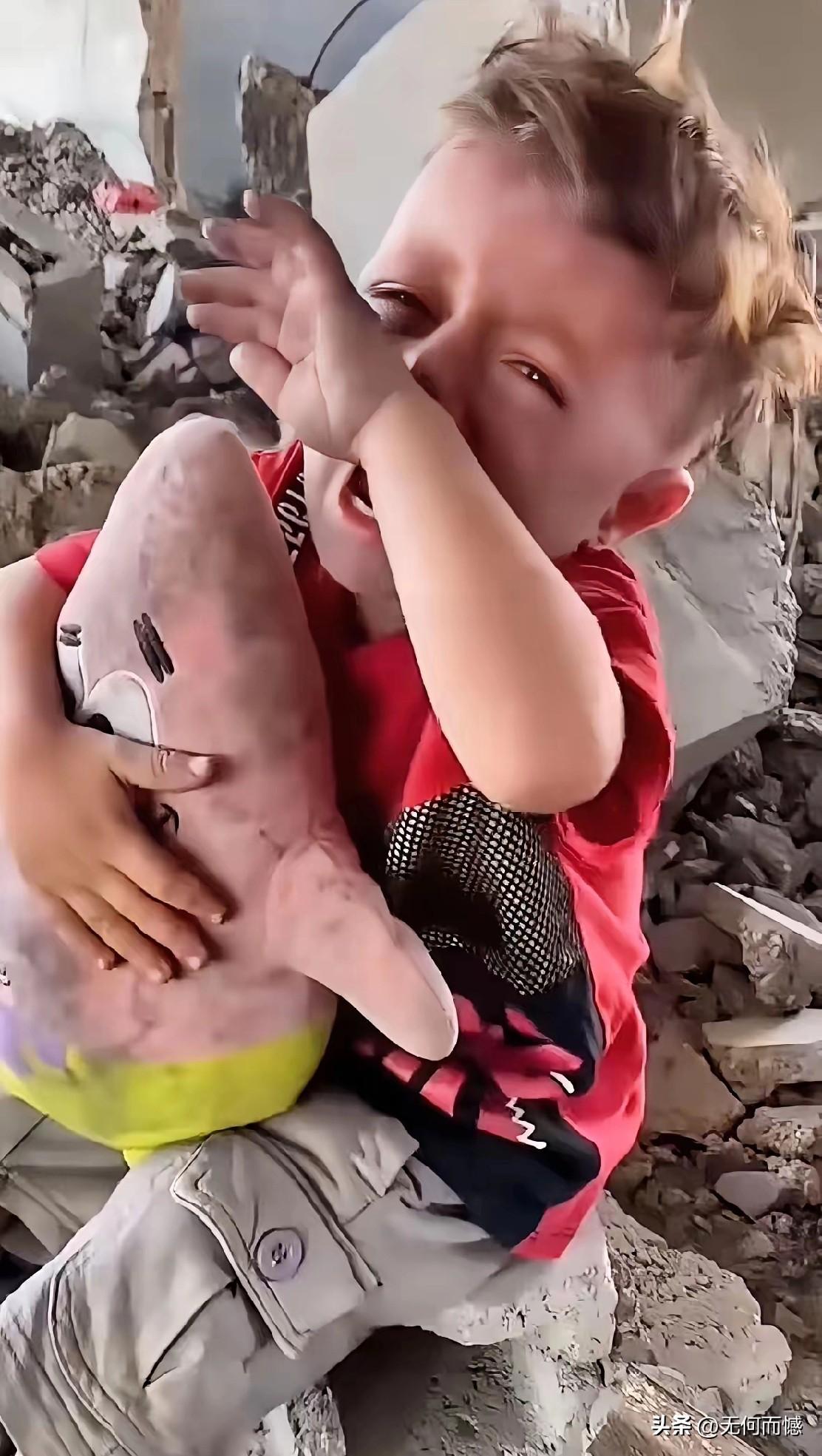 这是一个伊朗小朋友，他坐在一片废墟上，悲伤的痛哭了，怀里好像抱着一个玩具，不管是