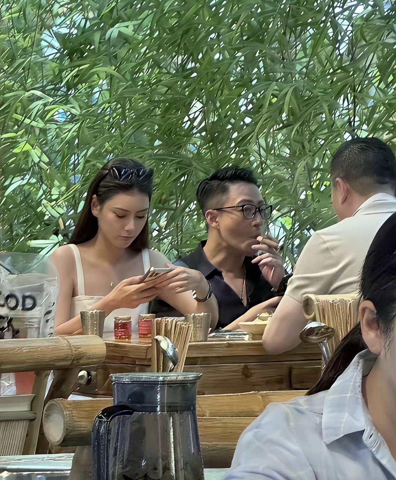 汪小菲与马筱梅旧照，汪小菲在饭桌上，与好友聊天，马筱梅坐在他旁边玩手机，很乖巧的