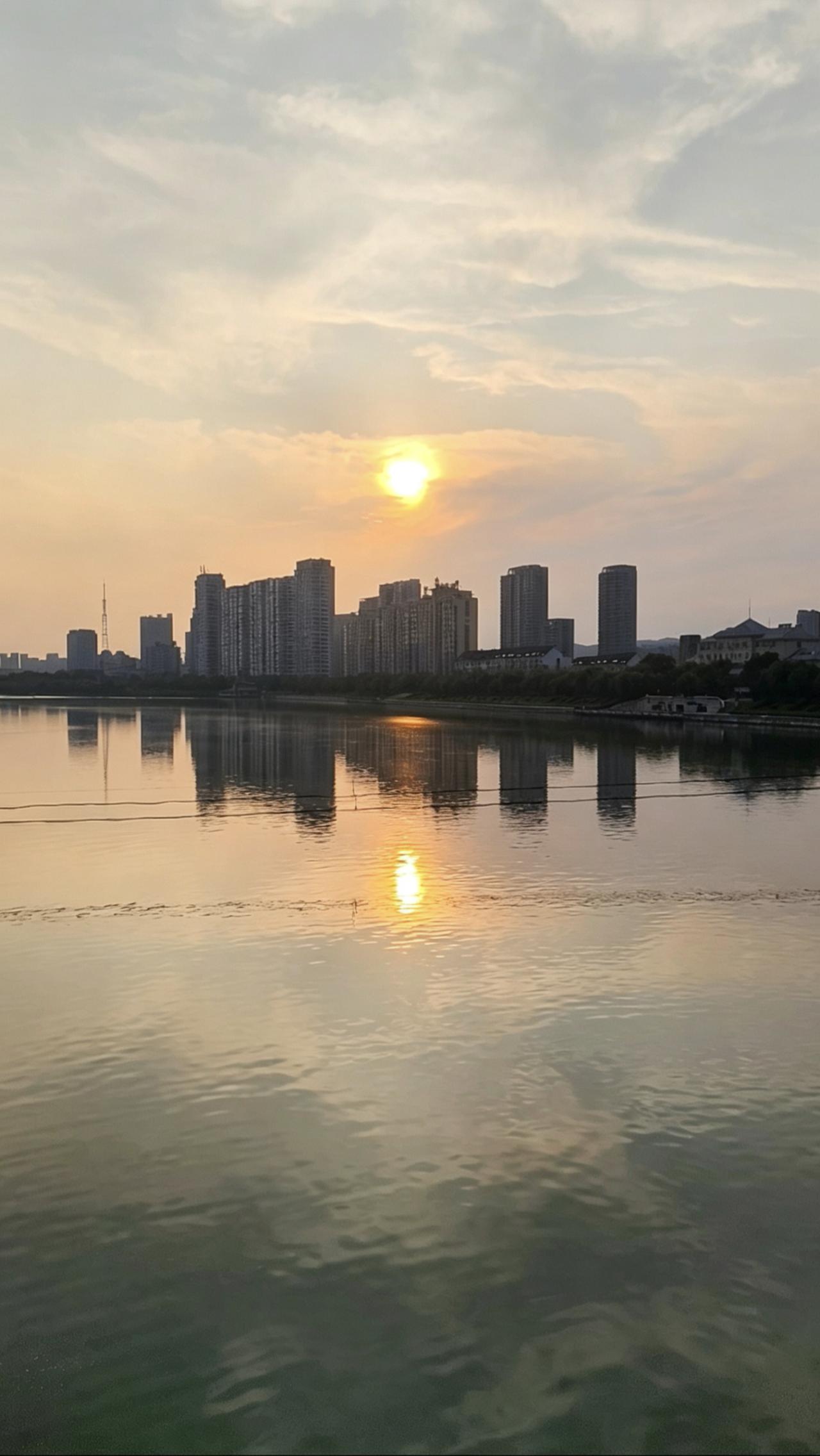 城市黄昏倒影，静谧的河面映照着落日余晖，宁静而美丽。