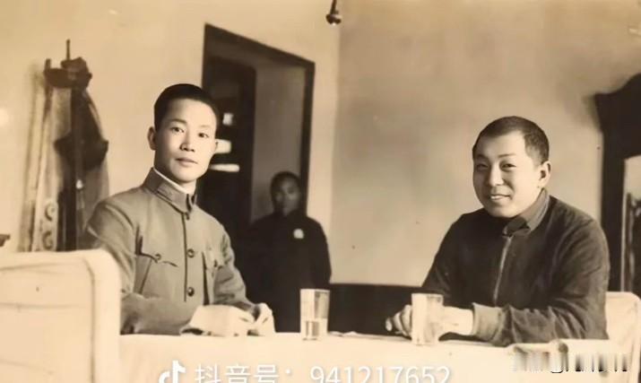 这是一张西安事变前夕拍摄于陕西潼关的老照片。屋内陈设朴素，两人隔桌对坐，桌上放着