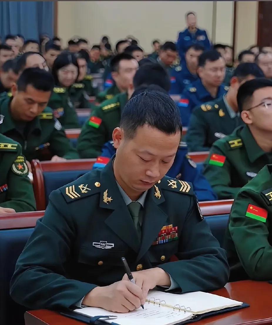 大家仔细看，坐在一群军官中间的这名士官真的是太帅了。
照片中，他身穿二级军士长军
