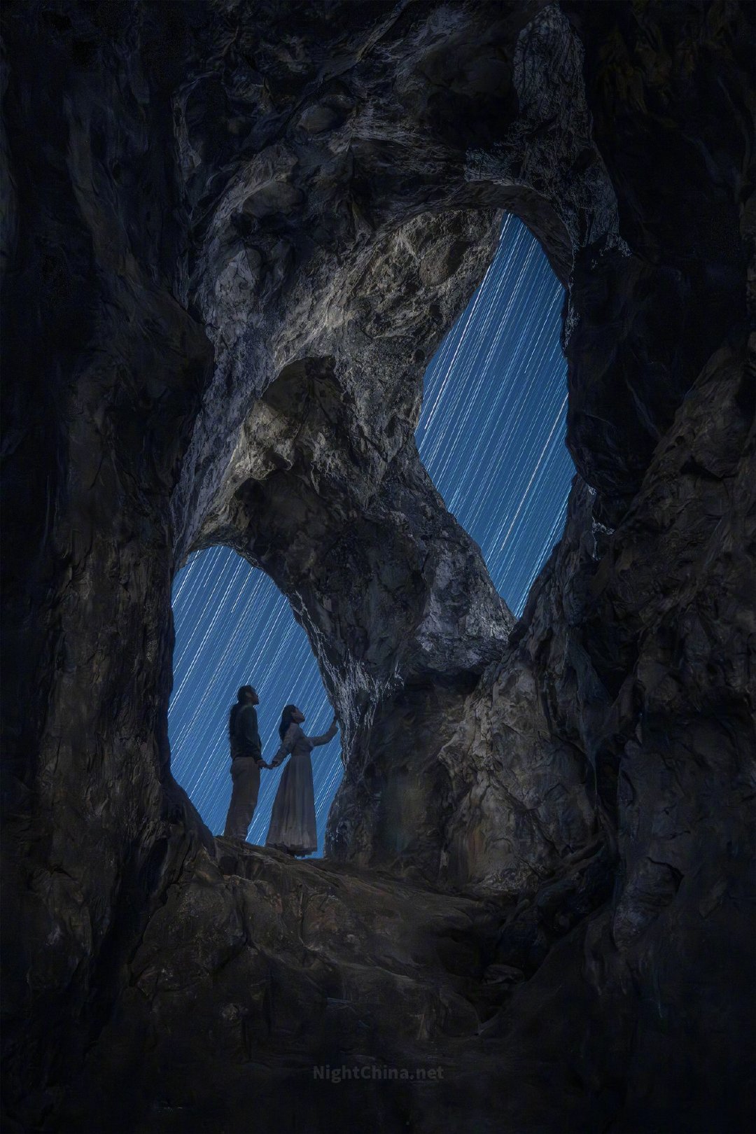 洞穴深处的岩壁像被岁月缓慢雕刻出的时间裂隙，两扇天窗将夜空引入山体，也把流动的星