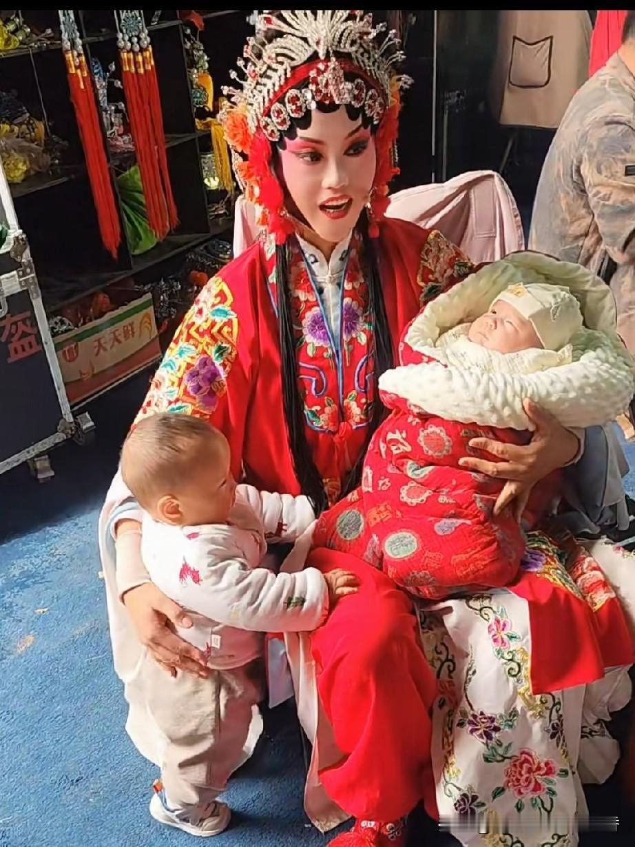 戏曲演员真的太辛苦了，这个女演员怀里抱着一个，手里还拉着一个，一个照看两个小孩，