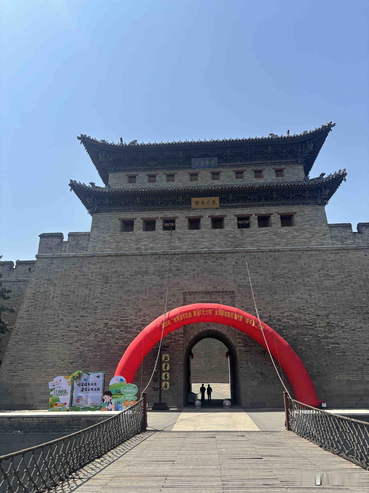 城下广场开阔整洁，读书活动的红色拱门点缀其间，古韵与烟火在此相逢。从北魏古都到如