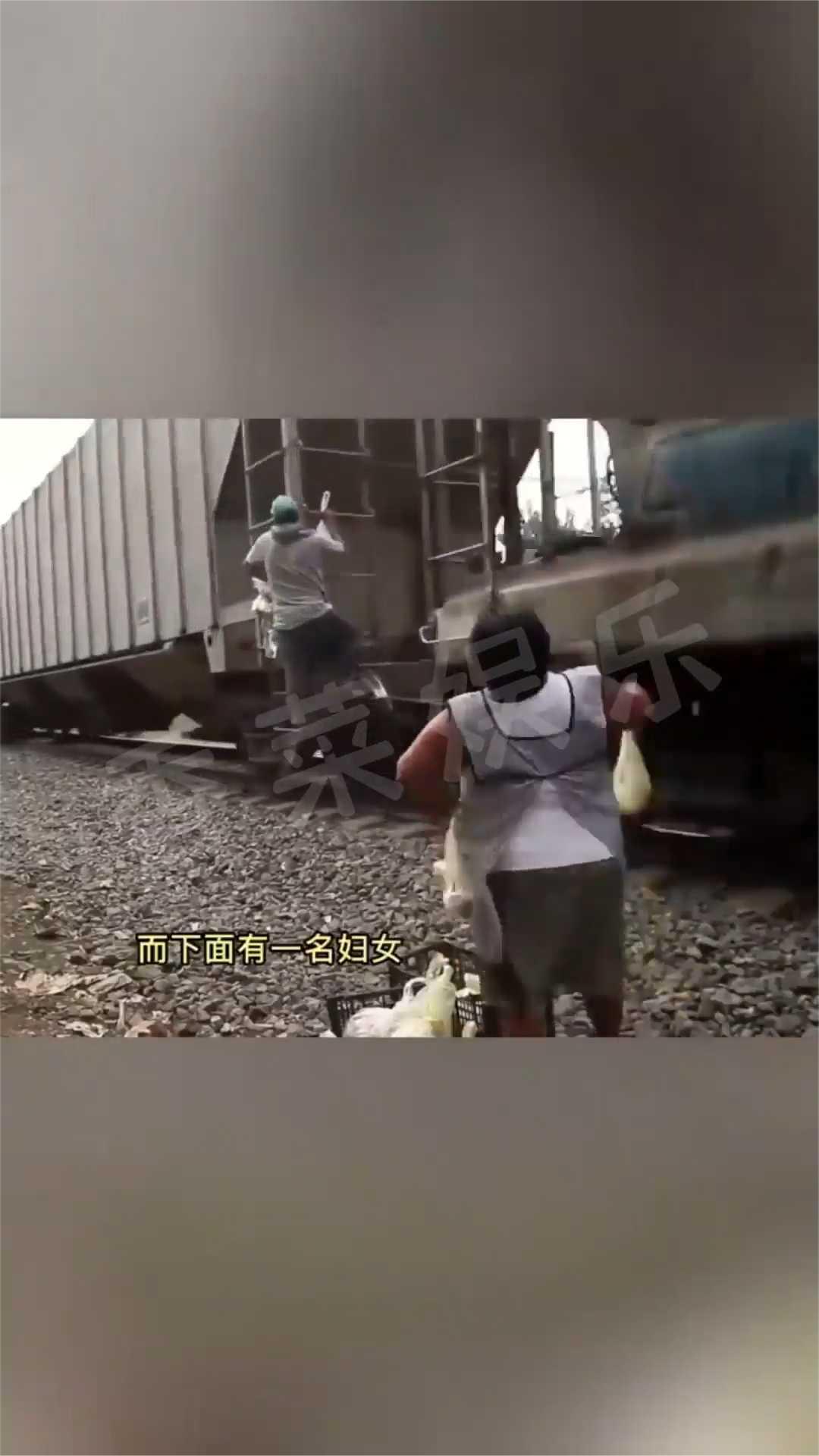 下面有一名妇女正在向火车上的人分发食物，火车的速度还是挺快的。上面的人要尽可能的