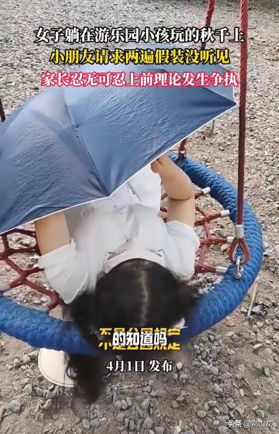 女子躺在游乐园儿童玩的秋千上玩手机，已经悠哉悠哉地躺了半天，小朋友想玩秋千，母亲
