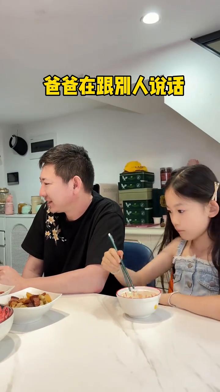爸爸在跟别人说话，女儿想吃旁边的菜，爸爸看到了，默默把菜放到女儿面前。女儿知道爸