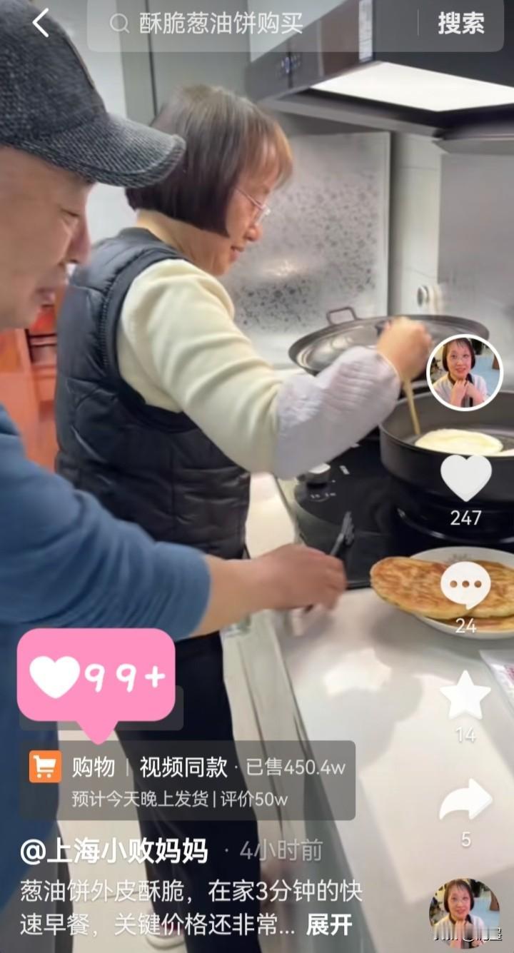 小败妈妈站在灶台前，身穿黑色马甲和米色上衣，此刻她正专注地用筷子夹着葱油饼翻面，
