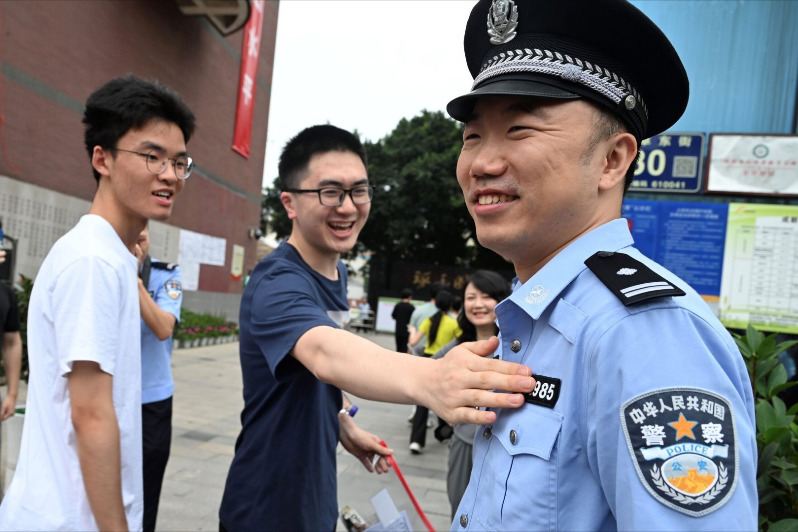 这位在高考考场外执勤的警察有了一项新的任务，进场的考生们去摸他胸前的警号，希望能