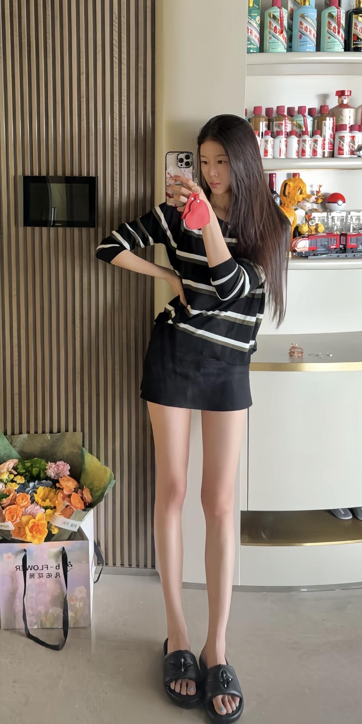 黑白色条纹长袖搭配黑色短裙，简约又不失时尚感。脚踩黑色厚底拖鞋，慵懒随性。手拿粉