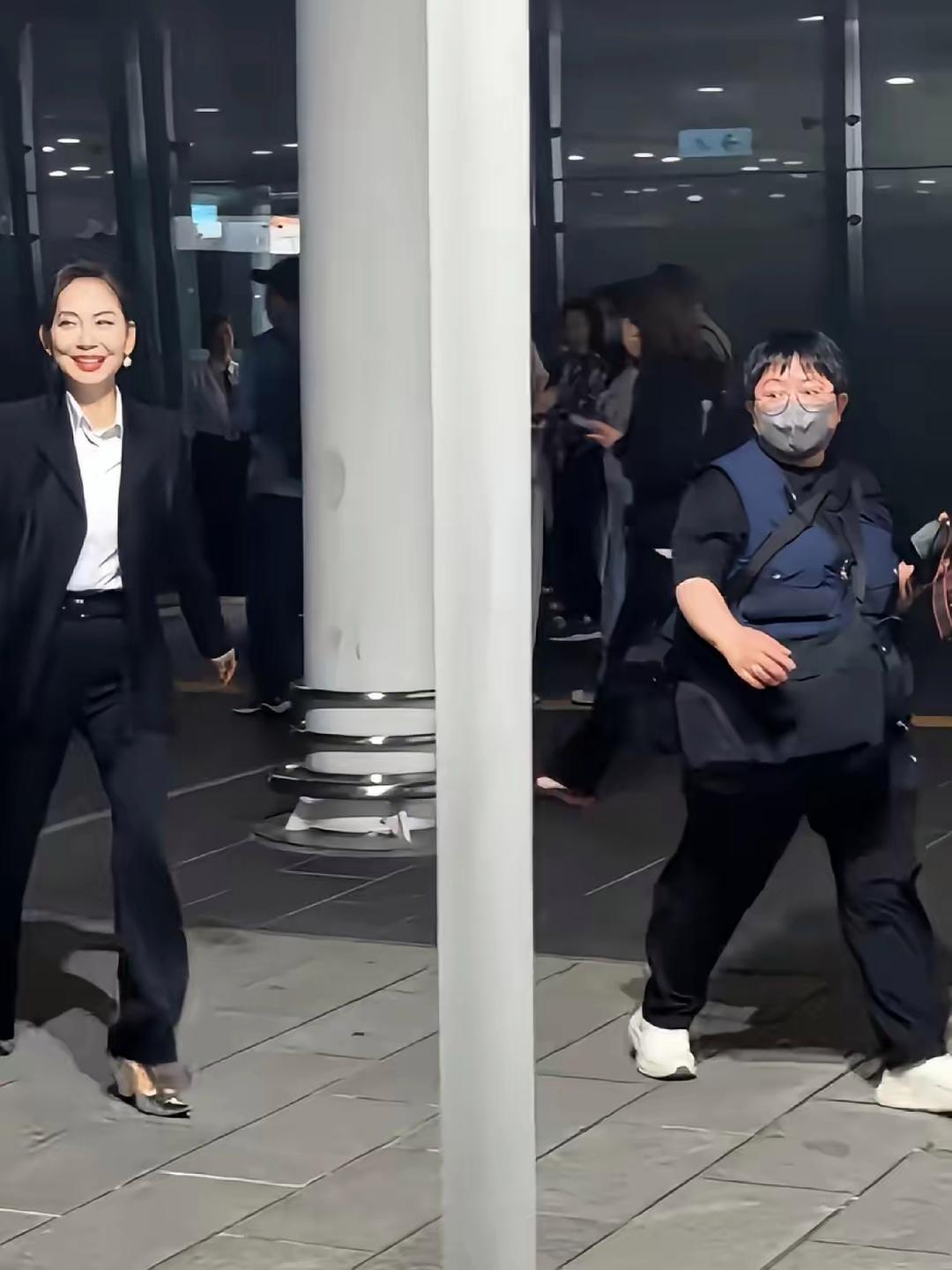 邝美云现身草蜢演唱会，她扎着丸子头，一身黑色小西装，搭配白色衬衫，手提包包，精神
