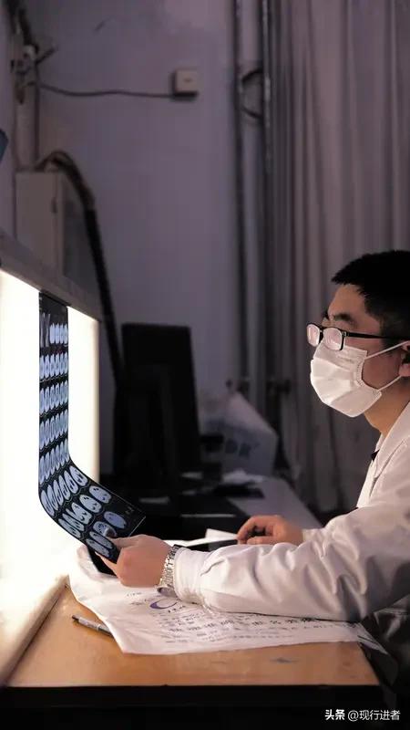 医者仁心是医生的初心

诊室外的走廊上，一位医者俯身蹲地，借着微光仔细查看CT片